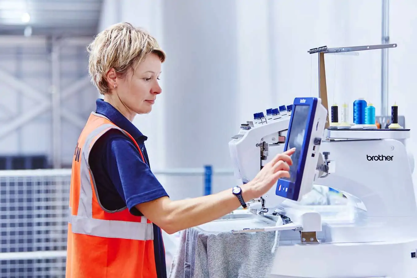 Woman using an embroidery machine in a warehouse