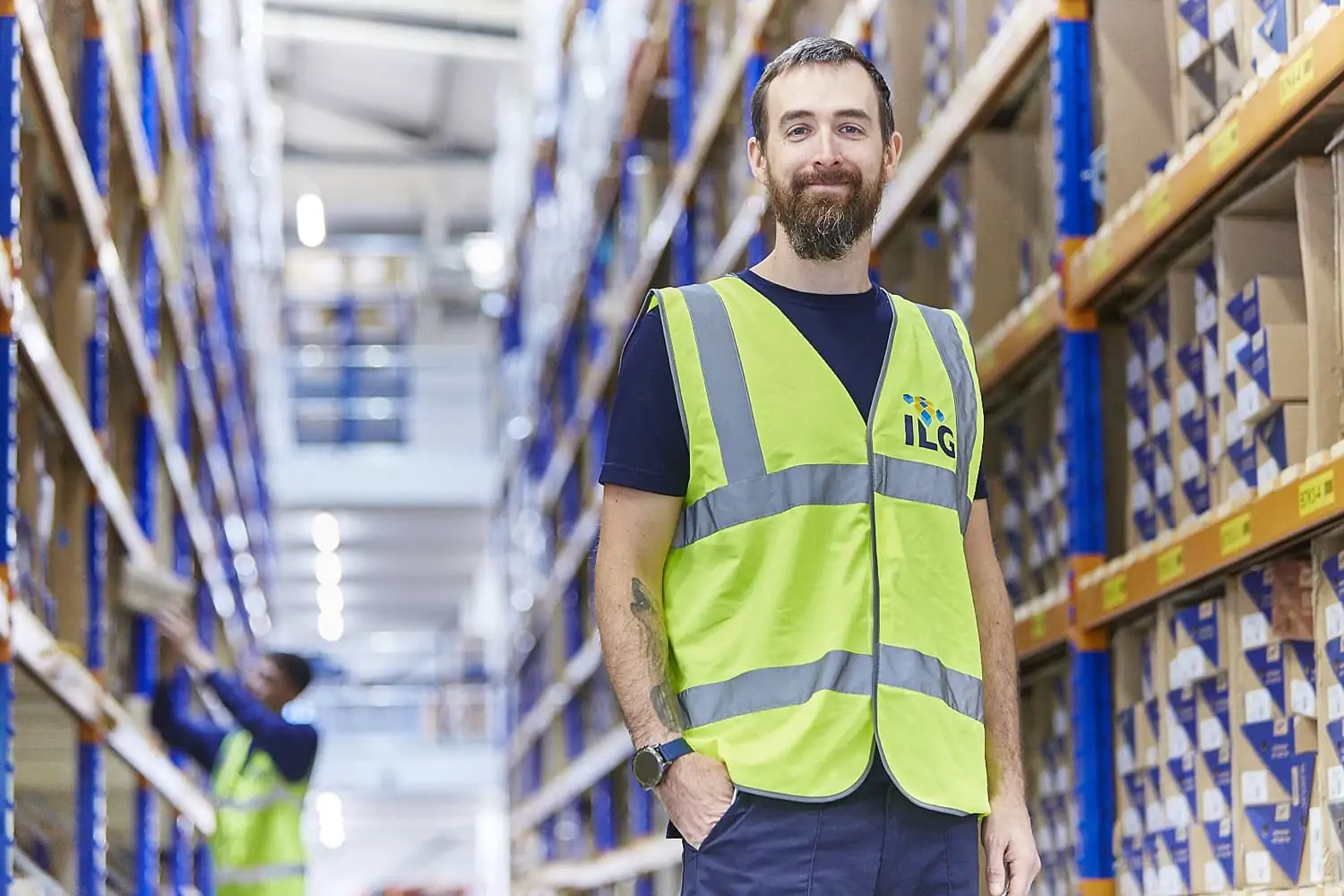 Man standing in a warehouse aisle smiling at camera