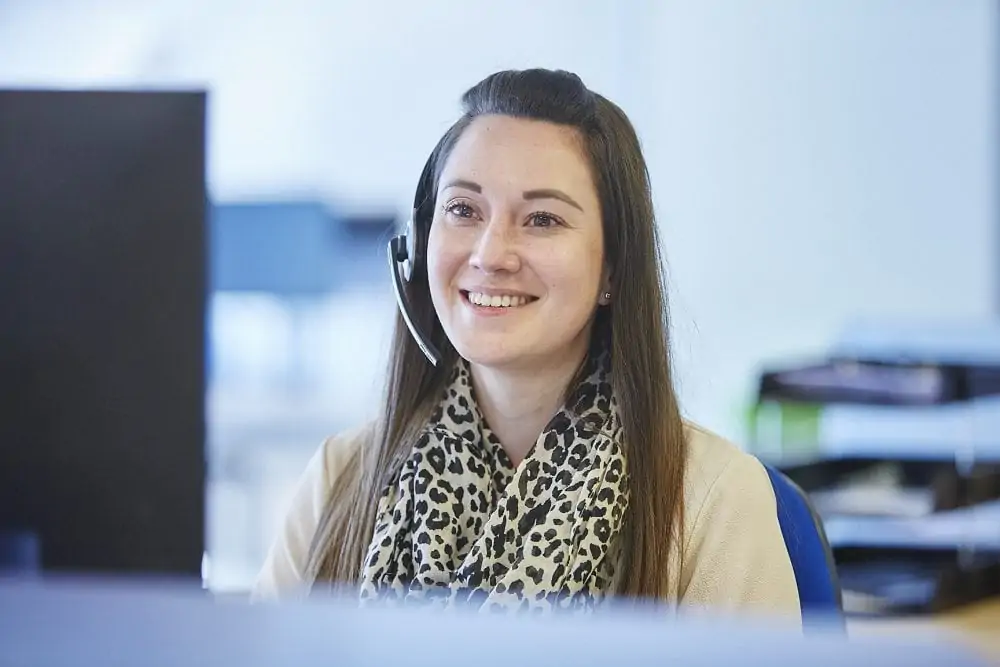 woman with headset on smiling at computer