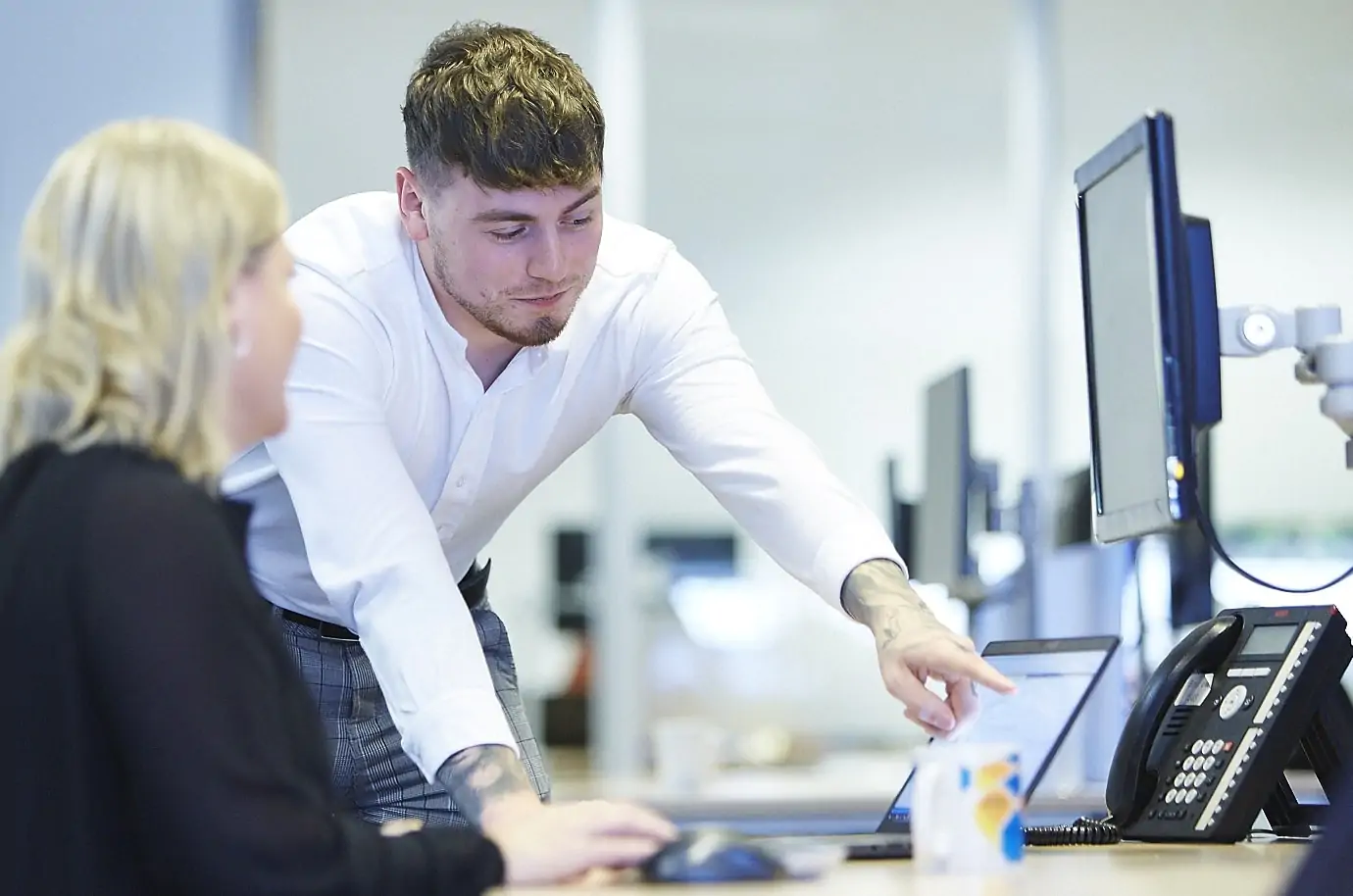 Man showing woman something on her laptop screen
