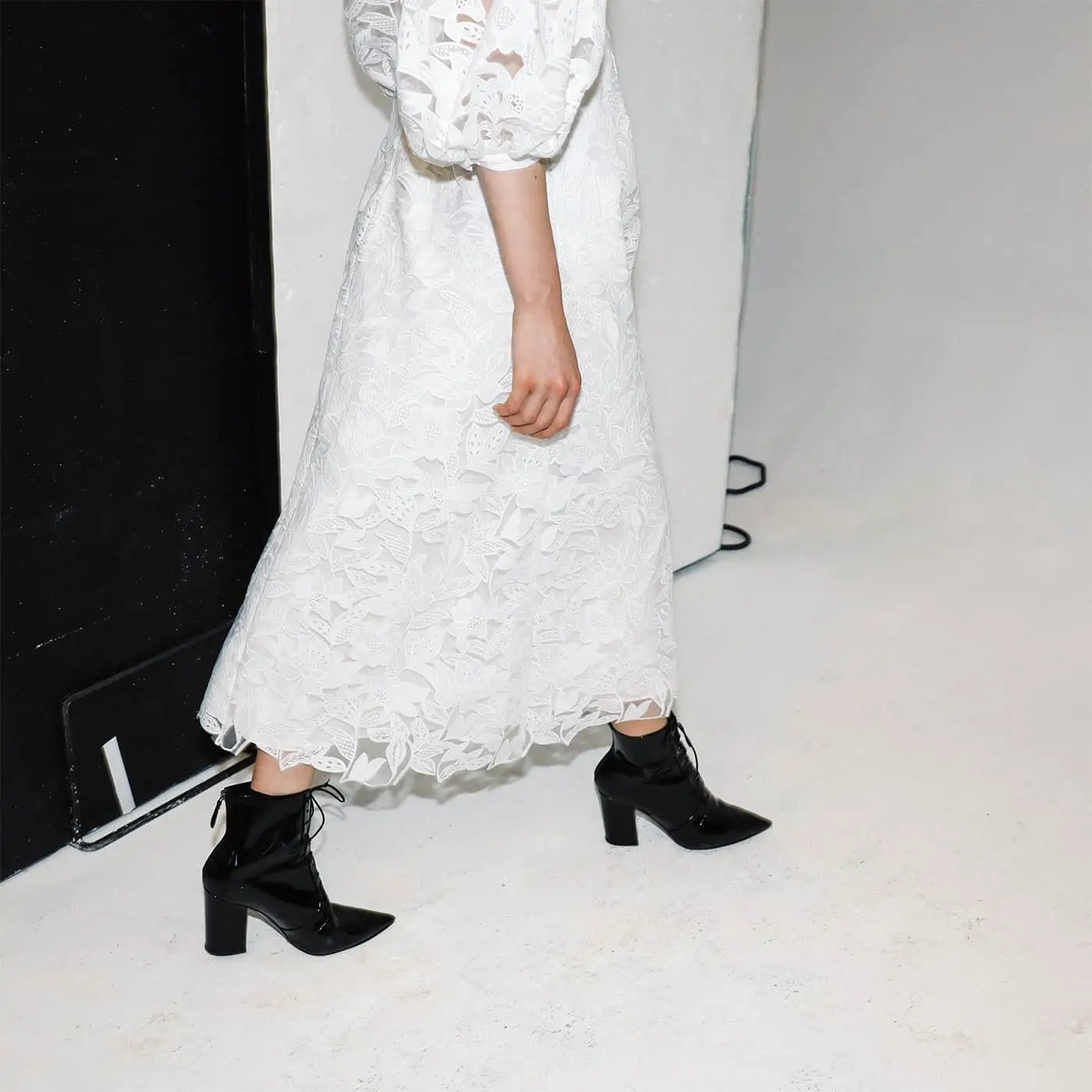 a lady wearing a white lacy dress and black heeled boots