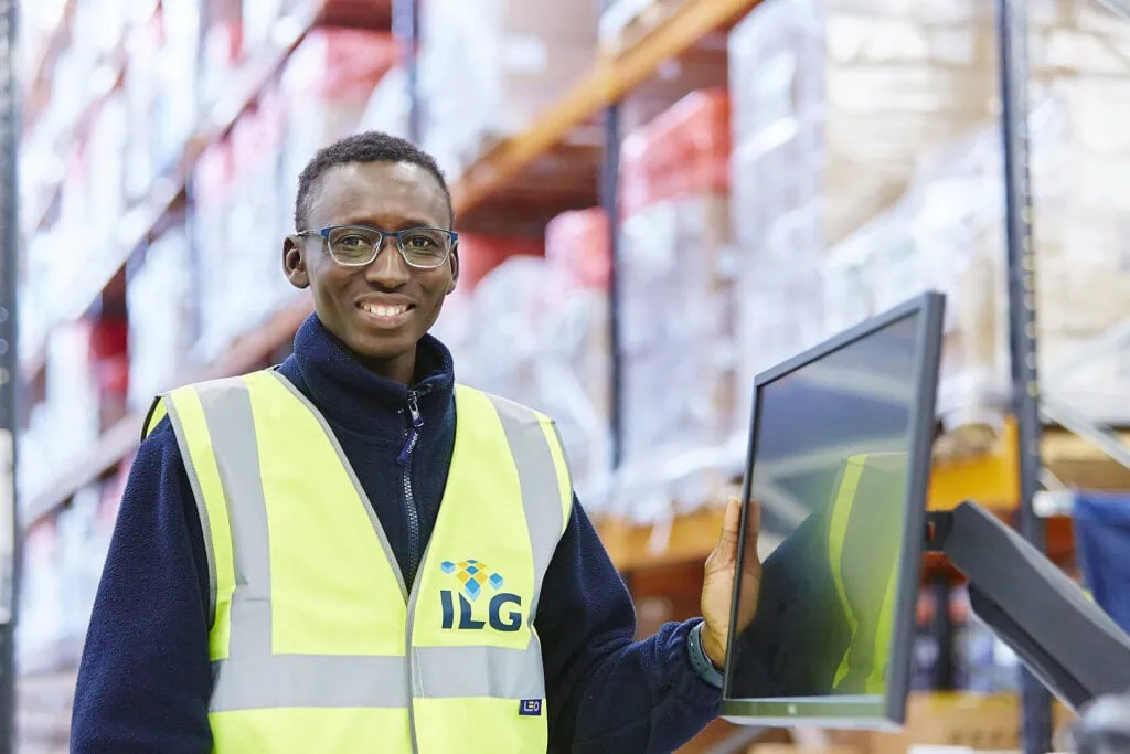 Man standing at computer with hi viz on