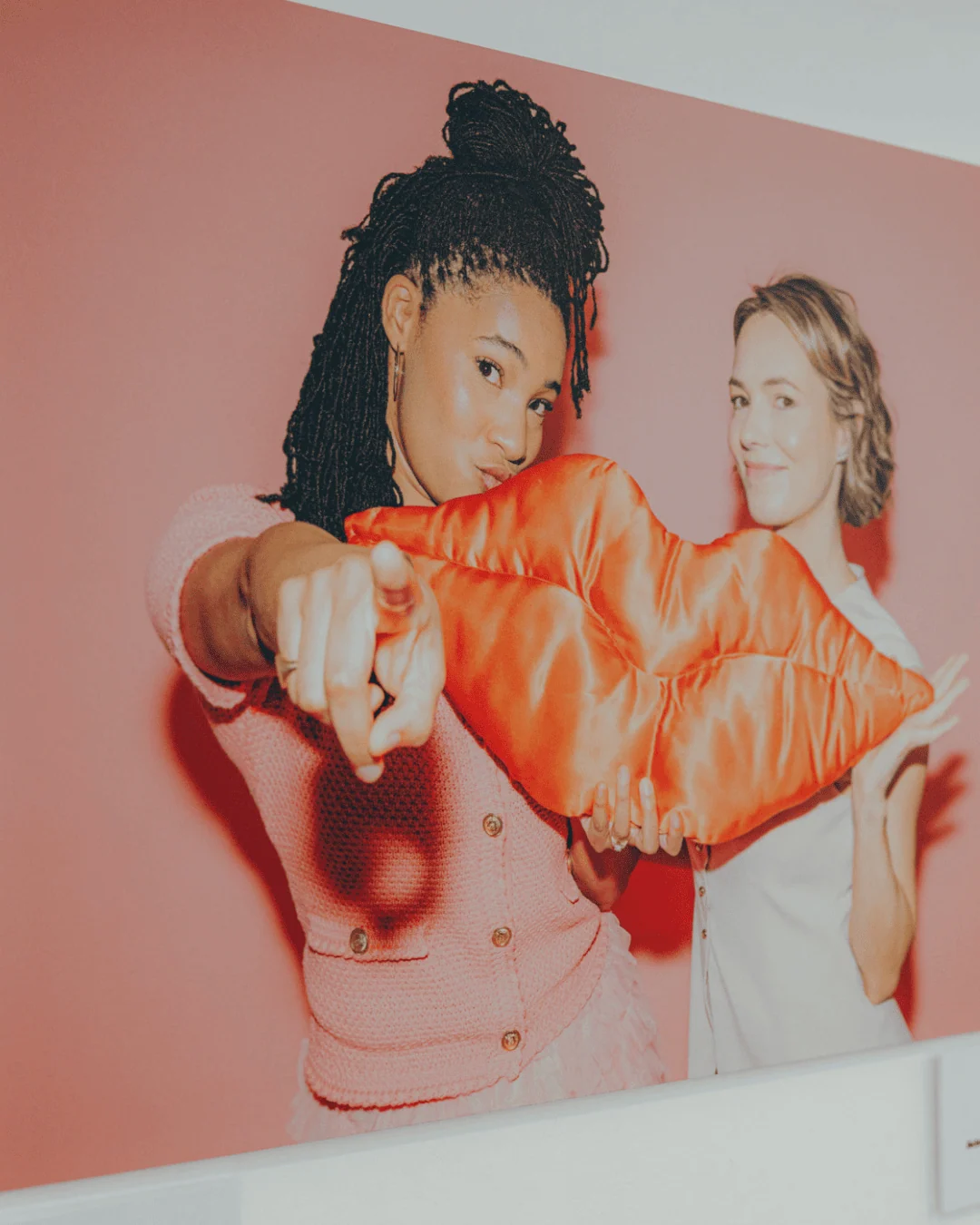 two ladies holding a pillow shaped as a lip